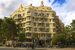 TBD Traveller - Stunning view of Casa Mila, Antoni Gaudi's iconic building in Barcelona, Spain, on a sunny day.