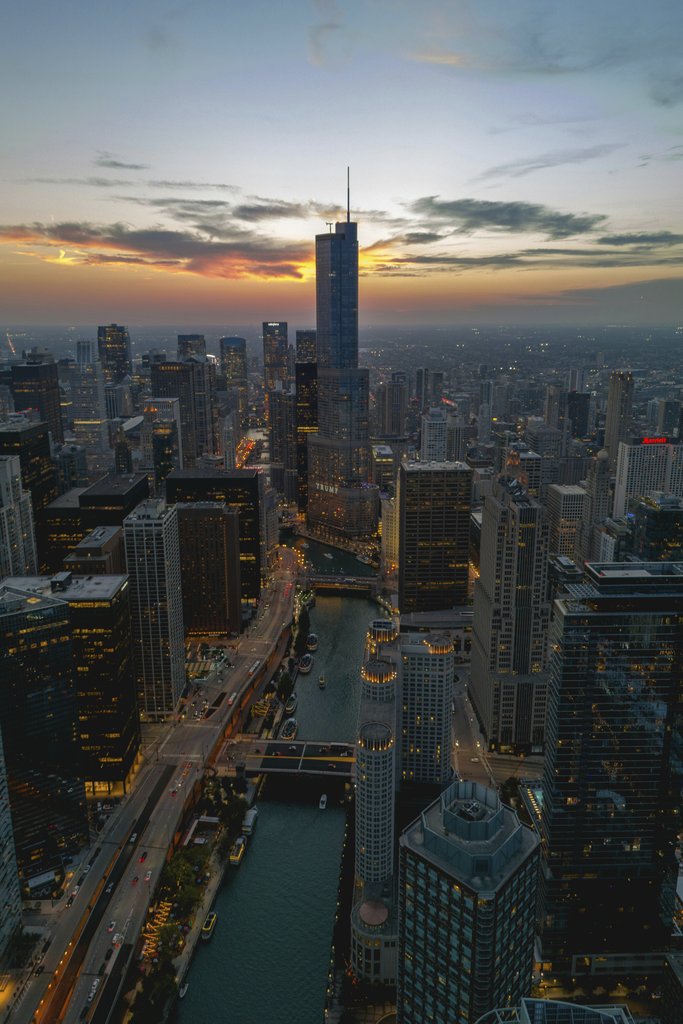 Willian Justen de Vasconcellos - Stunning aerial shot of Chicago's skyline at dusk with glowing city lights.