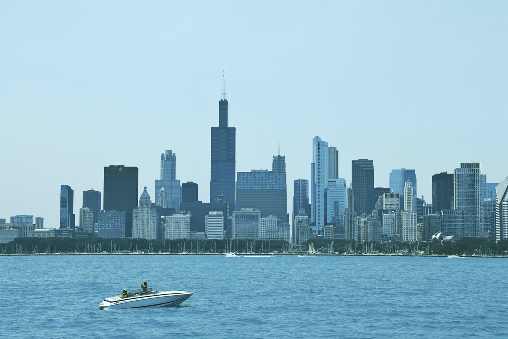 West Osee - A stunning view of Chicago's skyline featuring iconic skyscrapers and a speedboat on Lake Michigan.