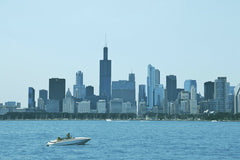 West Osee - A stunning view of Chicago's skyline featuring iconic skyscrapers and a speedboat on Lake Michigan.