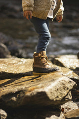 Daniel & Hannah Snipes - A child stands on rocks by a stream in North Carolina, showcasing durable boots.