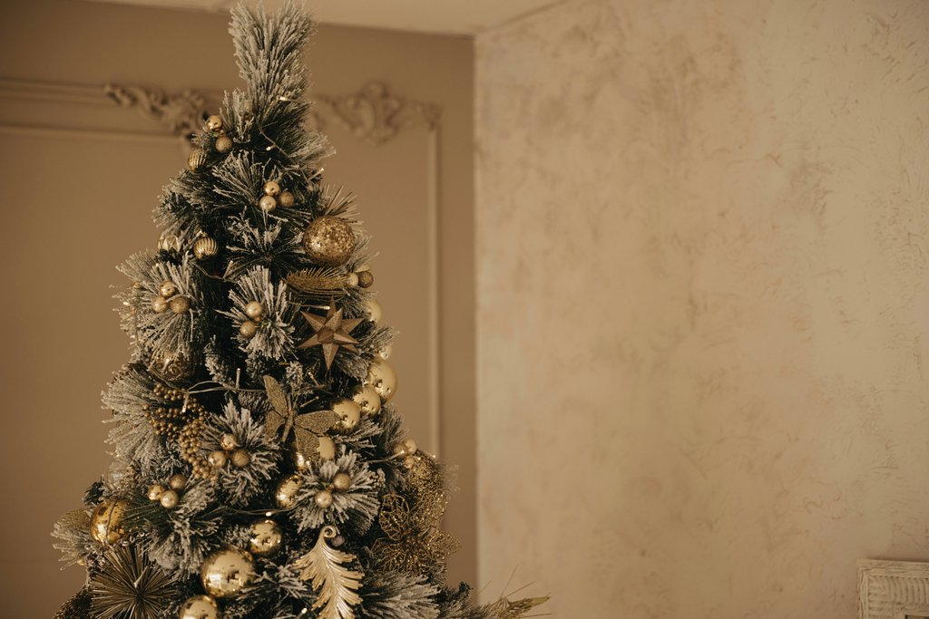 Lisett Kruusim - Elegant Christmas tree adorned with golden ornaments and festive decorations indoors.