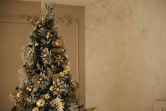 Lisett Kruusim - Elegant Christmas tree adorned with golden ornaments and festive decorations indoors.
