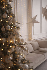Valeria Boltneva - Warm and inviting living room decorated with a Christmas tree, lights, and stars.