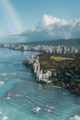 Jess Loiterton - A stunning aerial view of Honolulu's skyline with a rainbow over the ocean and cityscape.