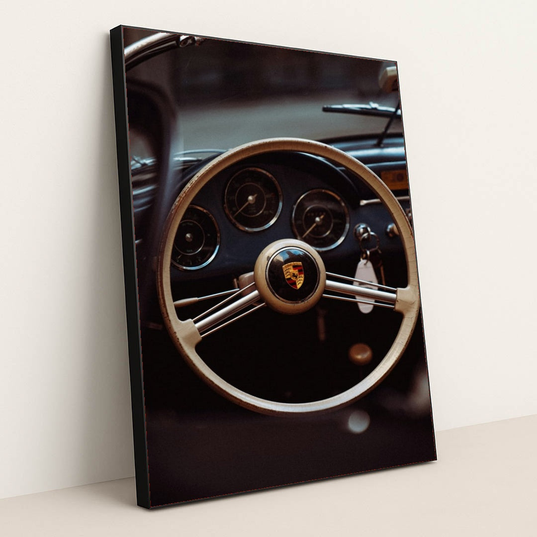 This photo shows the vintage steering wheel and gauges of a classic Porsche car, in a black frame.