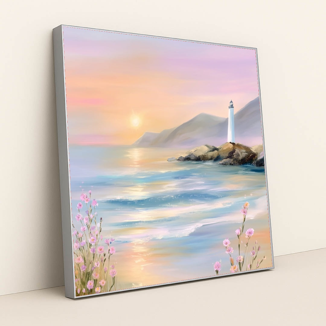 This artwork features a pastel seascape at sunset with a lighthouse on rocky cliffs and pink wildflowers, in a silver frame.