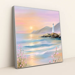 This artwork features a pastel seascape at sunset with a lighthouse on rocky cliffs and pink wildflowers, in a silver frame.