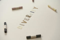cottonbro studio - A close-up of colored crayons surrounding cut-out letters spelling 'diversity' on a white background.