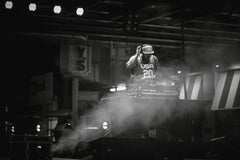 Arian Fernandez - DJ immersed in music on stage, surrounded by atmospheric smoke, creating an electrifying nightlife vibe.