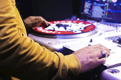 Suhellen Siffy - DJ operating a turntable with laptop in a vibrant nightlife setting.