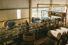 Los Muertos Crew - Interior view of a tequila factory with machinery and barrels in Mexico.