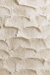 This artwork features overlapping fan-shaped textured cream plaster scales.