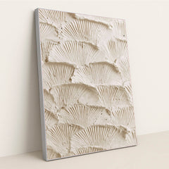 This artwork features overlapping fan-shaped textured cream plaster scales, in a silver frame.
