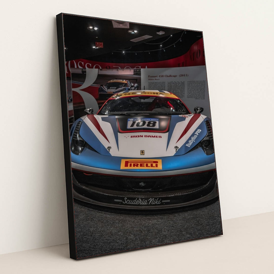 This photo shows the front view of a Ferrari 458 Challenge race car with Iron Dames and Pirelli branding in a museum, in a black frame.