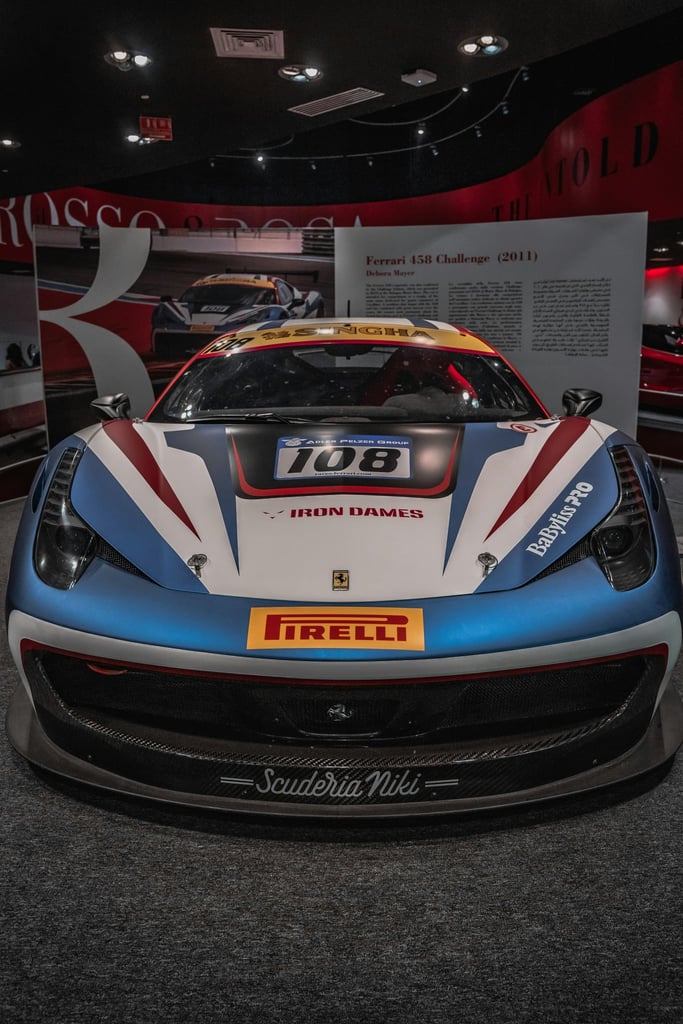Ferrari 458 Challenge Head-on Display in museum with bold blue and red racing stripes, showcasing car wall art aesthetic.
