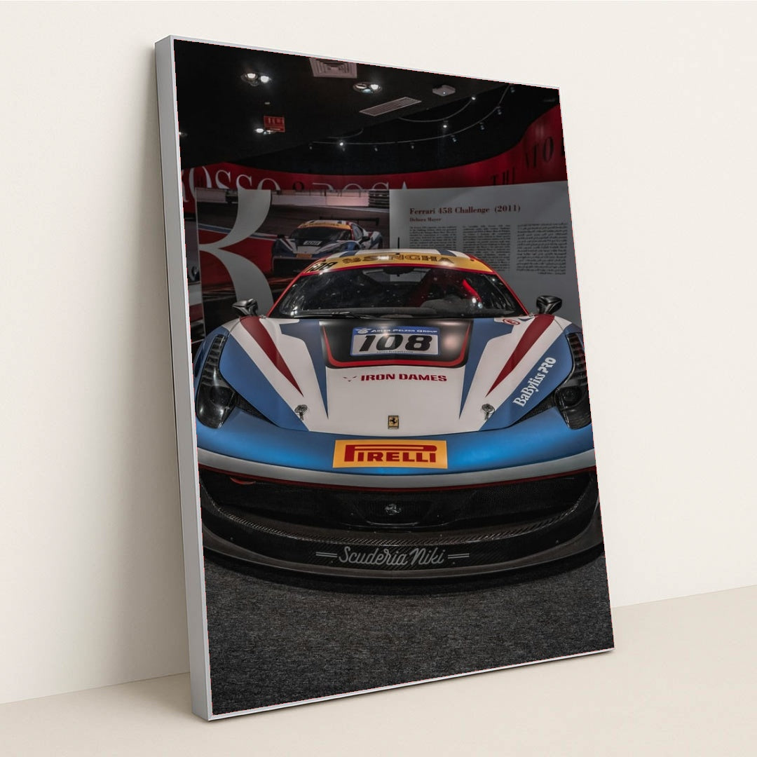 This photo shows the front view of a Ferrari 458 Challenge race car with Iron Dames and Pirelli branding in a museum, in a silver frame.