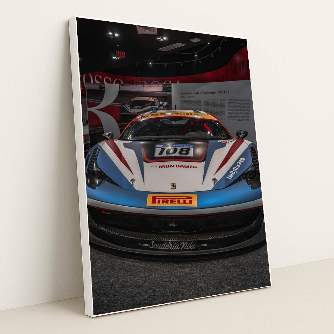 This photo shows the front view of a Ferrari 458 Challenge race car with Iron Dames and Pirelli branding in a museum, in a white frame.