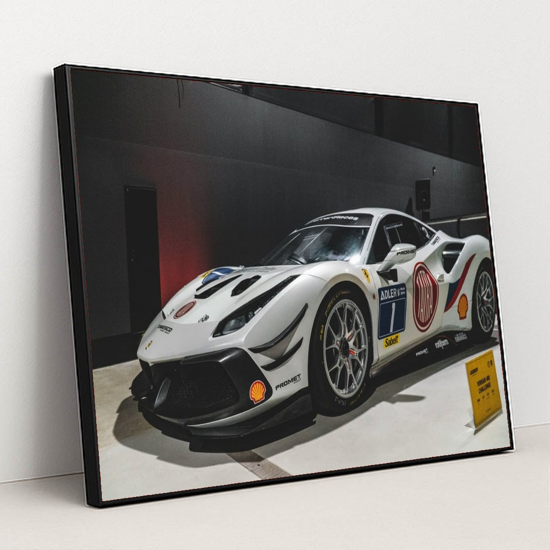 This photo shows a white Ferrari 488 Challenge Evo race car with sponsor decals displayed indoors, in a black frame.