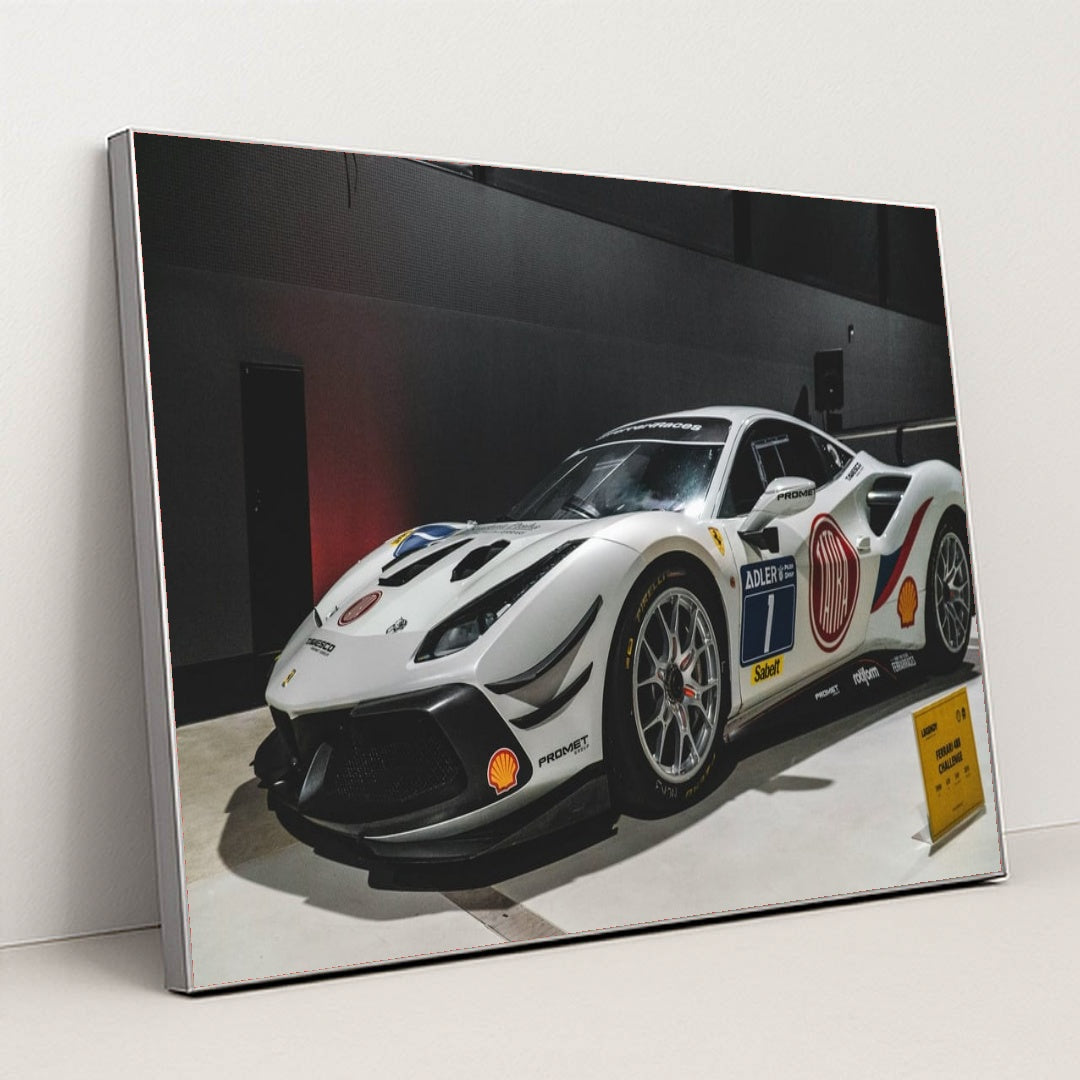 This photo shows a white Ferrari 488 Challenge Evo race car with sponsor decals displayed indoors, in a silver frame.