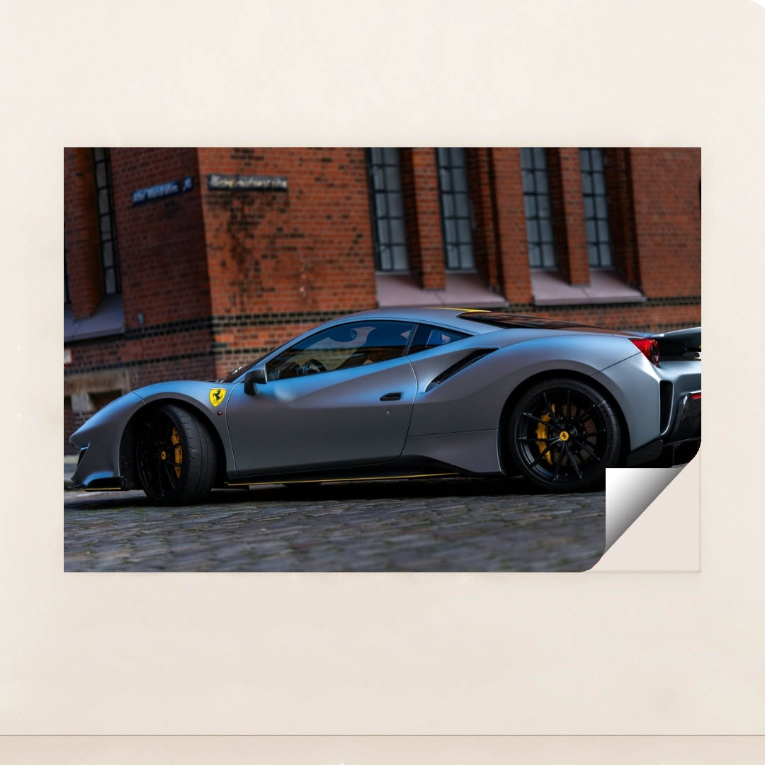 This photo shows a matte grey Ferrari 488 Pista with black wheels and yellow calipers parked by a brick building, unframed style.