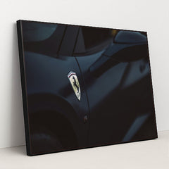 This photo shows a close-up of a dark blue Ferrari's front fender and side mirror with the Prancing Horse badge, in a black frame.