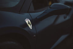Close-up of Ferrari's Dark Elegance featuring the iconic shield badge on dark glossy bodywork, perfect for car wall art.