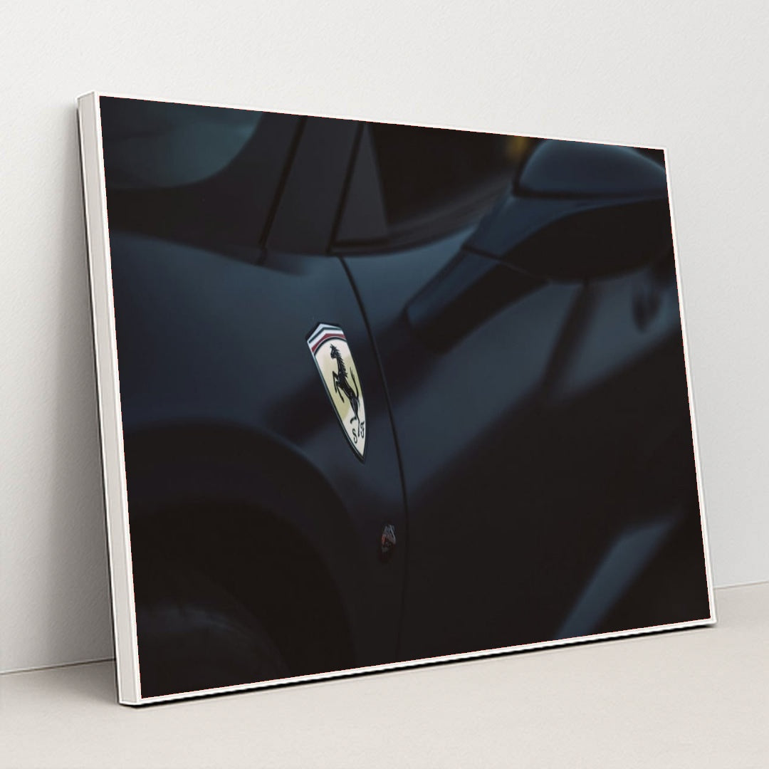 This photo shows a close-up of a dark blue Ferrari's front fender and side mirror with the Prancing Horse badge, in a white frame.