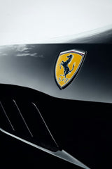 Ferrari Badge in Bold Contrast on a sleek black car, showcasing the vibrant yellow shield and prancing horse emblem for car wall art.