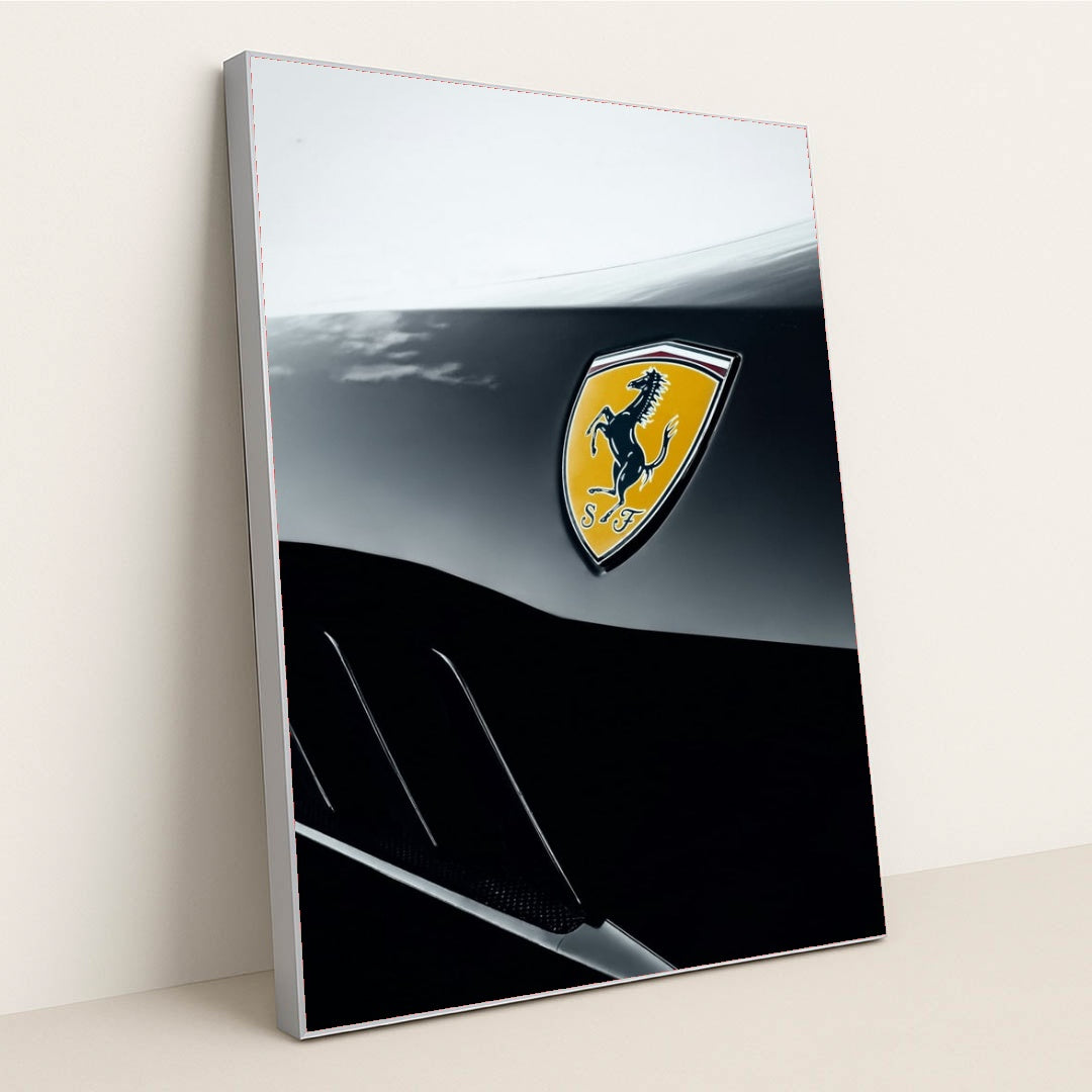 This photo shows a close-up of a Ferrari badge on a two-tone black and silver body panel, in a silver frame.