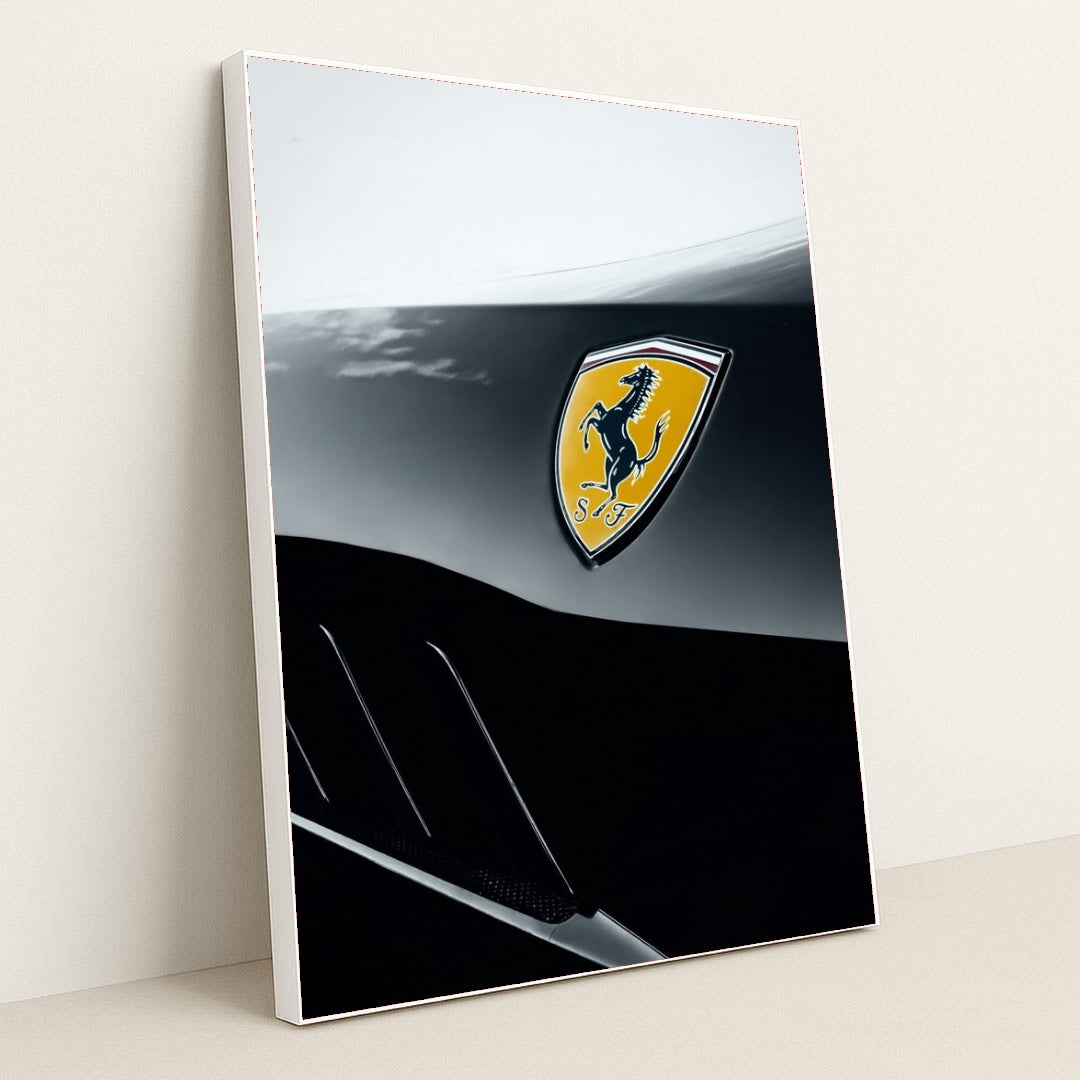 This photo shows a close-up of a Ferrari badge on a two-tone black and silver body panel, in a white frame.