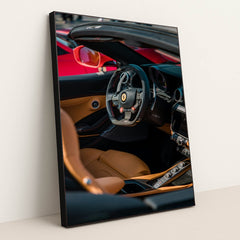 This photo shows the interior of a Ferrari convertible with tan leather seats and a carbon fiber steering wheel, in a black frame.