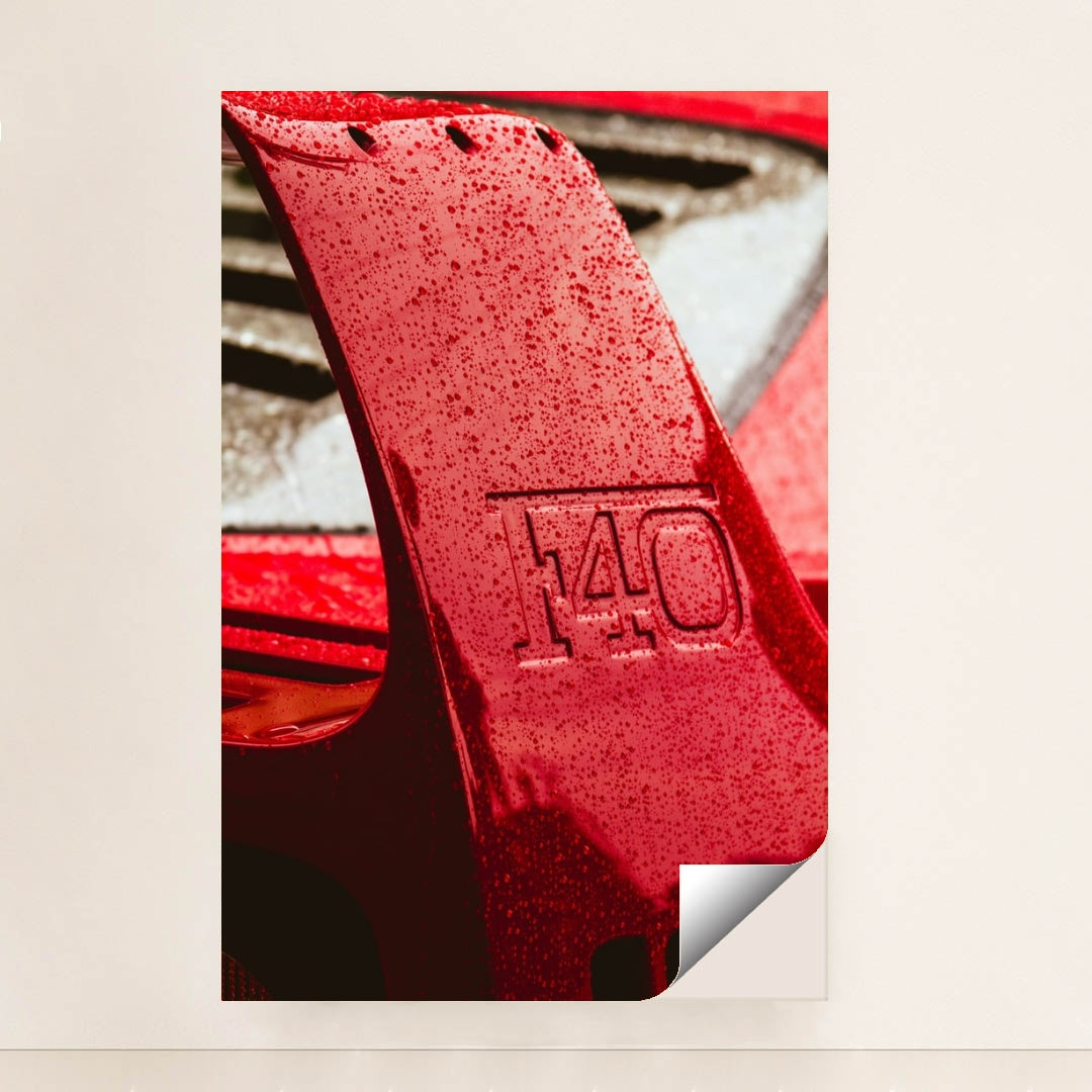 This photo shows a close-up of a wet red Ferrari F40 rear wing with raindrops, unframed style.