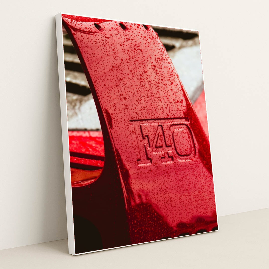This photo shows a close-up of a wet red Ferrari F40 rear wing with raindrops, in a white frame.