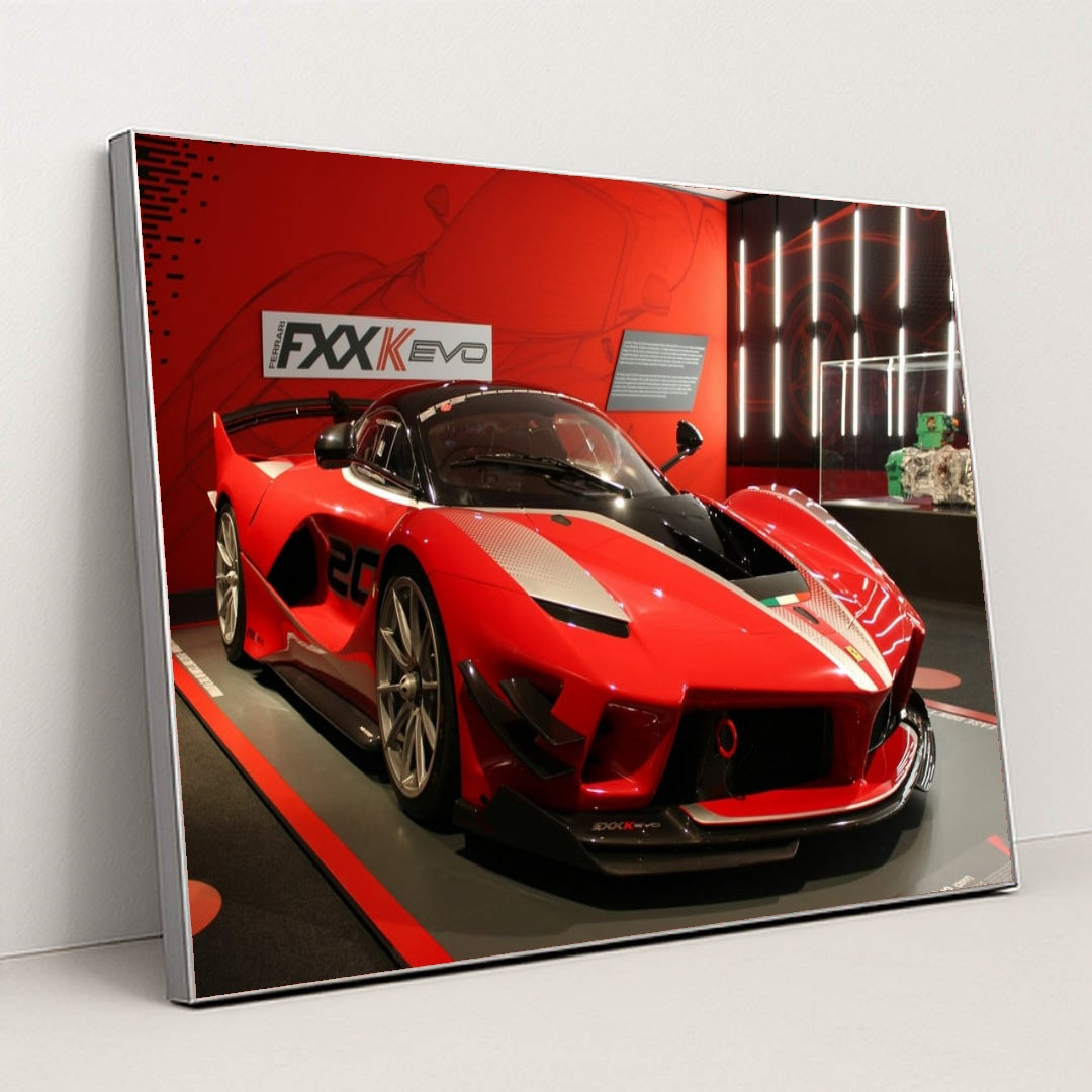 This photo shows a red Ferrari FXX-K Evo race car on display in a museum with red walls, in a silver frame.