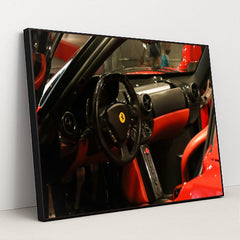 This photo shows the black and red leather interior of a Ferrari, featuring a round steering wheel and minimalist dash, in a black frame.