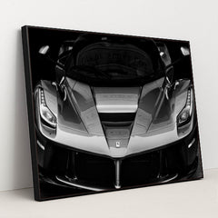 This photo shows the front view of a Ferrari hypercar in dramatic black and white, in a black frame.