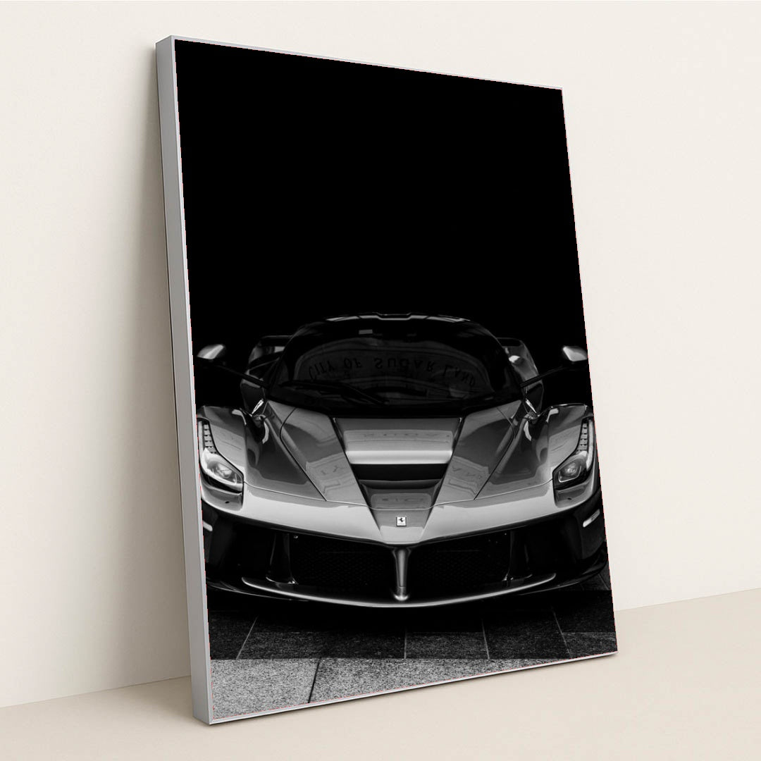 This photo shows a black and white front view of a Ferrari LaFerrari against a dark background, in a silver frame.