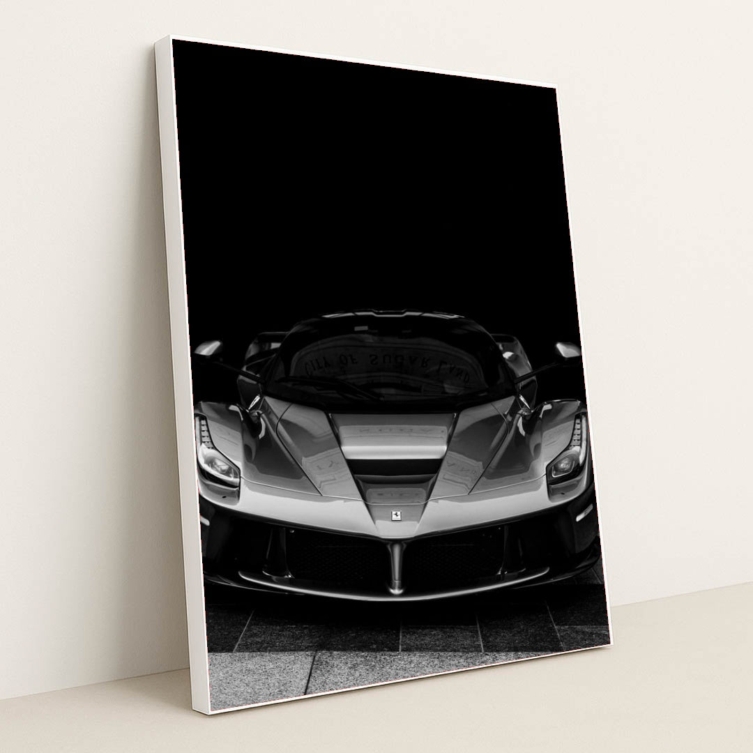 This photo shows a black and white front view of a Ferrari LaFerrari against a dark background, in a white frame.