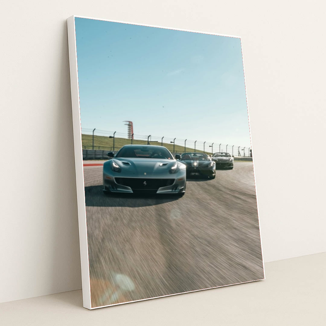This photo shows three grey Ferrari sports cars racing side by side on a sunny racetrack, in a white frame.