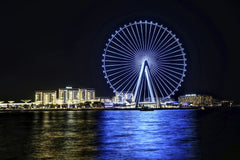 Hugo Sykes - Stunning nighttime view of Dubai's Ferris wheel reflecting in the water, showcasing city lights.