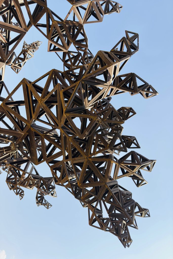 Mohamed Sameer - Intricate metal sculpture with geometric design set against a clear blue sky.
