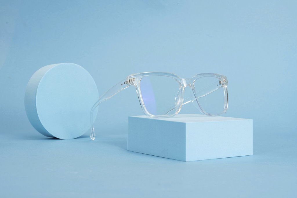 GlassesShop GS - Clear eyeglasses on blue geometric shapes, emphasizing minimalist design and clean lines.