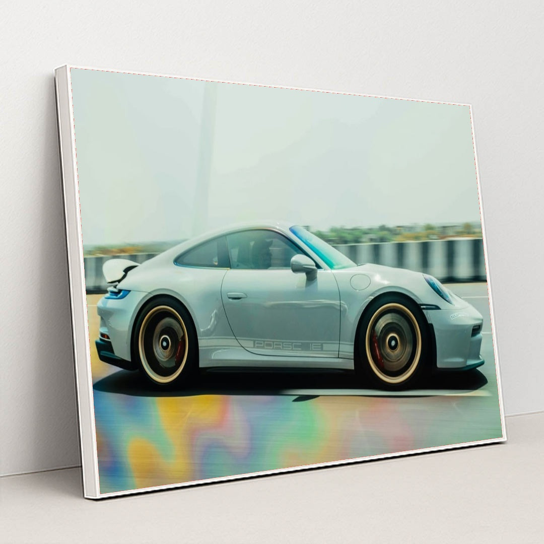 This photo shows a silver Porsche sports car in motion on a highway with colorful reflections on the road, in a white frame.