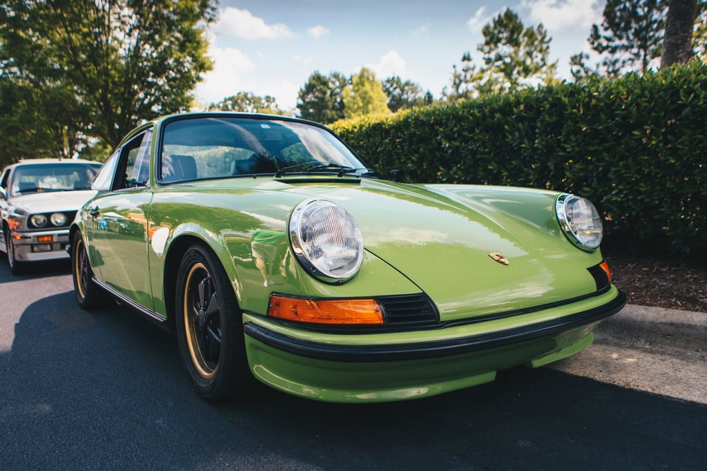 Classic Porsche 911 in Light Green parked under sunlight, showcasing vintage style and iconic design features.