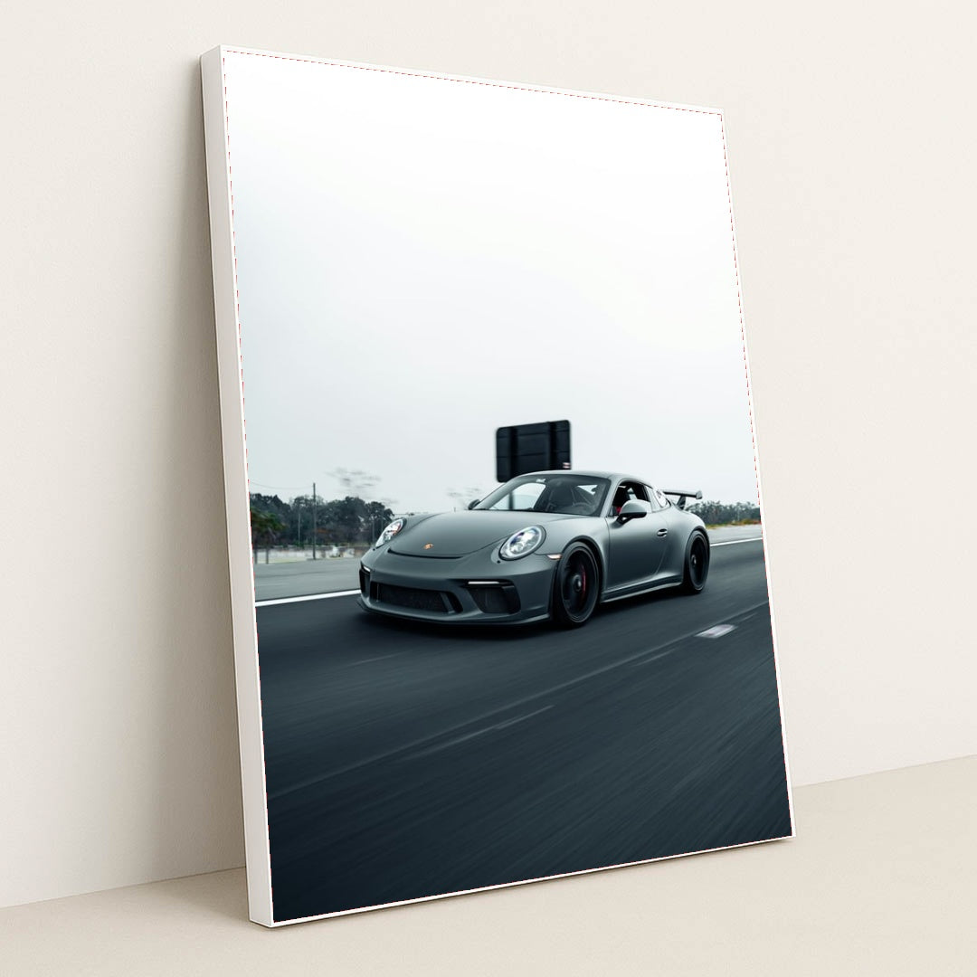 This photo shows a gray Porsche sports car driving fast on a highway with a blurred background, in a white frame.