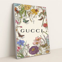 This artwork shows a floral Gucci design with colorful wildflowers, butterflies, and the Gucci logo on a pale background, in a silver frame.