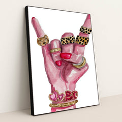 This artwork shows a hand with pink nails making a rock gesture, adorned with gold and animal print rings, and heart bracelets, in a black frame.