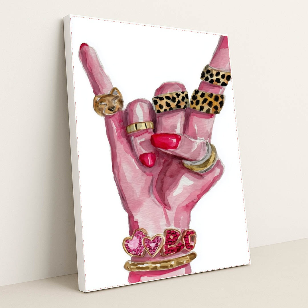 This artwork shows a hand with pink nails making a rock gesture, adorned with gold and animal print rings, and heart bracelets, in a white frame.