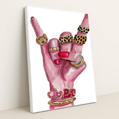 This artwork shows a hand with pink nails making a rock gesture, adorned with gold and animal print rings, and heart bracelets, in a white frame.